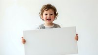 Happy curly-haired toddler boy holding blank white sign with both hands, smiling joyfully against neutral background for advertising and promotional use.