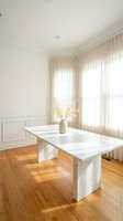 Modern minimalist dining room with white marble table, parquet flooring, sheer curtains and neutral decor for contemporary home interior design.