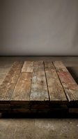 Rustic wooden pallet table surface with weathered planks against neutral gray wall background for product display and photography mockups.