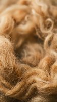 Natural brown wool fiber texture with soft curly strands for textile crafts and knitting projects.