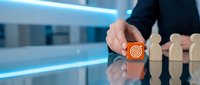 Professional businessman selecting target icon from wooden blocks on modern office desk representing strategic goal setting and business objectives.
