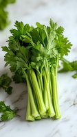 Fresh green celery stalks with bright leaves on marble background, macro food photography for healthy eating and cooking concepts.