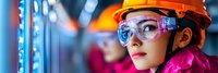 Young Asian female engineer wearing orange hard hat and safety glasses in modern industrial facility with colorful lighting and advanced technology equipment.