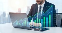 Professional businessman analyzing financial growth data on laptop with digital charts and upward trending graphs overlay in modern city office environment.