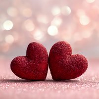 Two red glittery hearts on sparkling pink surface with soft bokeh lights background for Valentine's Day romance love celebration greeting cards.