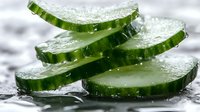 Fresh cucumber slices with water drops on wet surface, macro shot showing crisp texture and natural green color. Healthy organic vegetable closeup.
