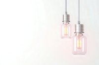 Two glowing vintage edison bulbs in glass jar pendants hanging against soft pink background, creating minimal modern industrial lighting design.