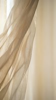 Flowing cream tulle fabric with delicate sparkles creates elegant draping texture for wedding dress or formal gown design projects.