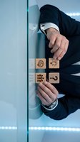 Businessman arranging wooden blocks with innovation icons representing creative thinking, problem solving and strategic planning in modern office environment.