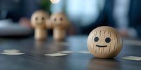 Wooden emoji character with neutral expression on blurred background with two similar figures, representing social anxiety, loneliness or isolation concept.