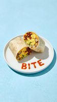 Halved breakfast burrito with scrambled eggs, chorizo, avocado, and potatoes on a white plate with hot sauce lettering on blue background.