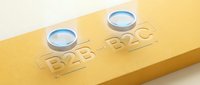 B2B E2C text engraved on gold surface with two water droplets sitting on top, representing business communication and liquid solutions.