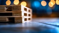 Wooden pallets stacked on reflective surface with soft golden bokeh lights and blue background creating atmospheric industrial composition.