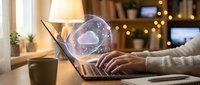Cloud computing technology concept with glowing holographic cloud icon above laptop keyboard in cozy home office workspace with warm lighting.