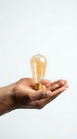 Hand holding glowing vintage Edison bulb on white background symbolizing creativity innovation and bright ideas for business concepts.