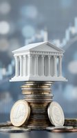 White classical bank building model on stack of coins representing financial stability and economic growth with blurred city background.