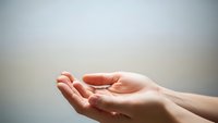 Open cupped hands reaching upward in gesture of receiving, giving or prayer against soft blurred background for spiritual and wellness concepts.
