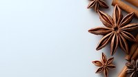 Aromatic star anise and cinnamon sticks arranged on light background with copy space, creating minimalist food composition for cooking and baking.