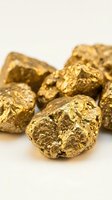 Raw gold nuggets with metallic shine on neutral background for investment and precious metals trading concepts.
