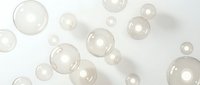 Floating transparent soap bubbles on white background creating dreamy atmosphere for cosmetic and beauty product presentations.
