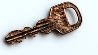 Old brass key with worn patina and textured surface casting soft shadow on white background, isolated object suitable for design projects and security concepts.