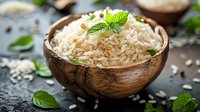 Steamed basmati rice garnished with fresh mint leaves in rustic wooden bowl, perfect for healthy meal preparation.