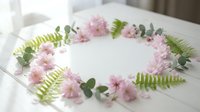 Delicate pink cherry blossoms and green fern leaves arranged in elegant oval frame on white surface for spring wedding invitations and romantic designs.