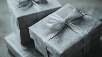 Elegant silver wrapped gift boxes with shimmering ribbon bows arranged in soft focus composition, creating romantic and luxurious holiday atmosphere.