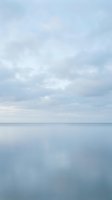 Serene seascape with calm waters and soft cloudy sky, reflecting peaceful atmosphere. Suitable for backgrounds, wellness, and nature-themed designs.