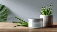 Minimalist cosmetic jar with aloe vera plant in ceramic pot on wooden surface against gray wall, natural skincare and beauty product photography.