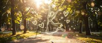 Magical park scene with glowing heart shapes floating through sunlit trees creating romantic atmosphere for wedding invitations and love concepts.