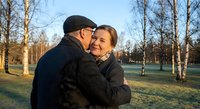 Happy senior couple embracing in autumn park during golden hour sunset. Elderly man and woman sharing romantic moment outdoors among bare trees in warm evening light.
