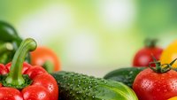 Fresh organic vegetables with water droplets on green bokeh background for healthy cooking and nutrition concepts.