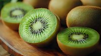 Fresh ripe kiwi fruit cut in half showing vibrant green flesh and black seeds on wooden cutting board, macro close up view for healthy food concept.