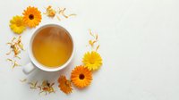 Herbal tea with fresh and dried gerbera flowers arranged on white background, overhead view for wellness and natural beverage design projects.