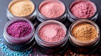 Colorful mineral makeup powder collection in open jars showing pink, coral, bronze and gold cosmetic pigments for beauty and skincare routines.