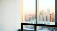 Modern office interior with glass table displaying transparent bar charts against city skyline at sunset for business presentations and data visualization.