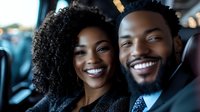 Young African American couple smiling in car backseat, showing genuine joy and connection. Professional business attire and natural curly hair style create modern lifestyle scene.