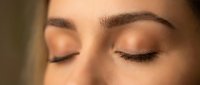 Young woman with closed eyes showcasing natural makeup and long eyelashes in warm lighting for beauty and skincare concepts.