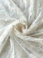 Delicate white tulle fabric with pearl embellishments swirled in elegant spiral pattern, creating romantic texture for wedding and special occasion designs.