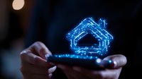 Glowing blue house icon floating above smartphone in dark environment, representing smart home technology and digital real estate solutions.