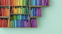 Colorful rainbow bookshelf with organized books arranged by color spectrum from red to purple on wooden shelves against mint green wall for education and reading.