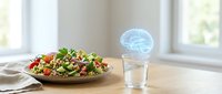 Fresh healthy salad bowl with mixed greens and vegetables on wooden table next to glass of water with glowing brain hologram for nutrition and mental health.