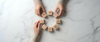 Wooden blocks spelling LOVE arranged in circle by two people hands on marble surface for romantic relationship concept and wedding planning designs.