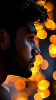 Side profile portrait with dramatic orange bokeh lights creating magical atmosphere against dark background, highlighting facial features in artistic lighting.