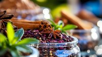 Aromatic spices and herbs with star anise, cinnamon sticks and dried elderberries in glass jar on rustic wooden surface with soft bokeh lights and fresh leaves.