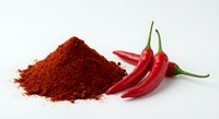 Red chili pepper powder pile with fresh hot peppers isolated on white background for cooking spice seasoning culinary ingredient food preparation.