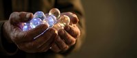 Hands holding glowing crystal spheres with blue and amber light, representing energy, magic, and spiritual power for wellness and healing concepts.