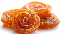 Orange spiral candy rolls with sugar coating on white background isolated for confectionery and dessert design projects.