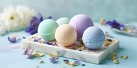 Colorful bath bombs on marble tray with dried flowers, creating spa-like atmosphere for relaxation and self-care rituals.
